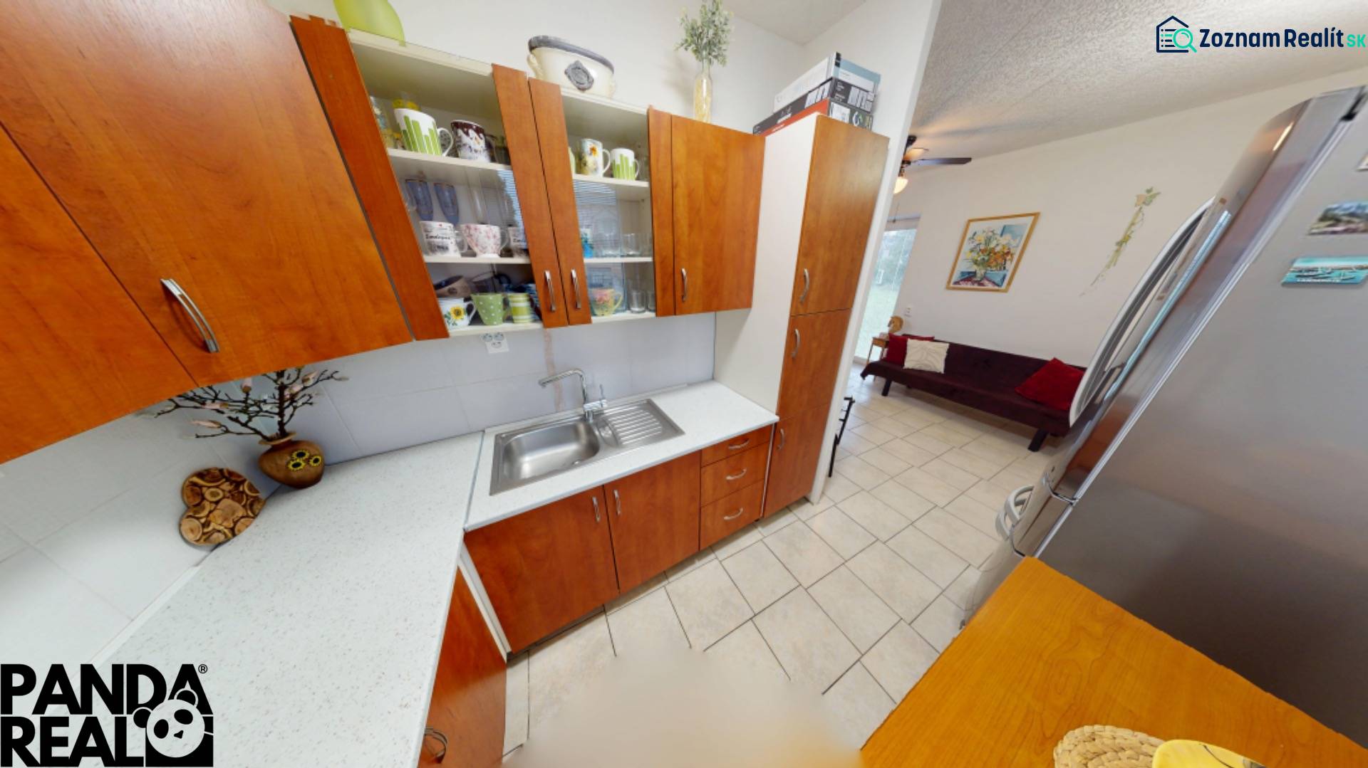 NAJLACNEJŠÍ 3- izbový byt v Topoľčanoch, neďaleko ZKW - Kuchyňa v 3-izbovom byte s dreveným dekorom skriniek, chladničkou a jedálenským kútom.