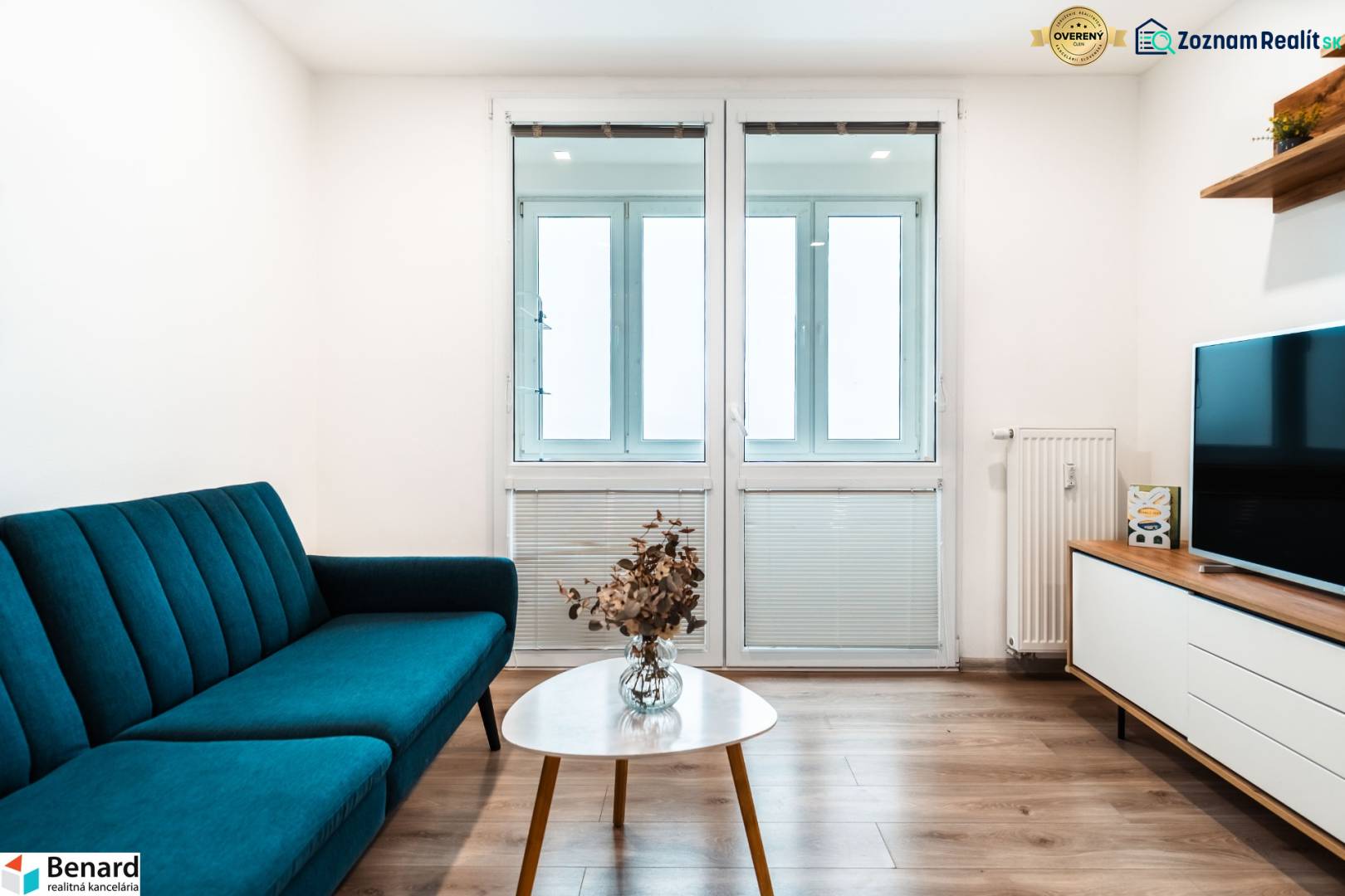 Útulný 2-izbový byt na prenájom - Obývacia izba v 2-izbovom byte so sedačkou, televízorom a podlahou s dreveným dekorom.