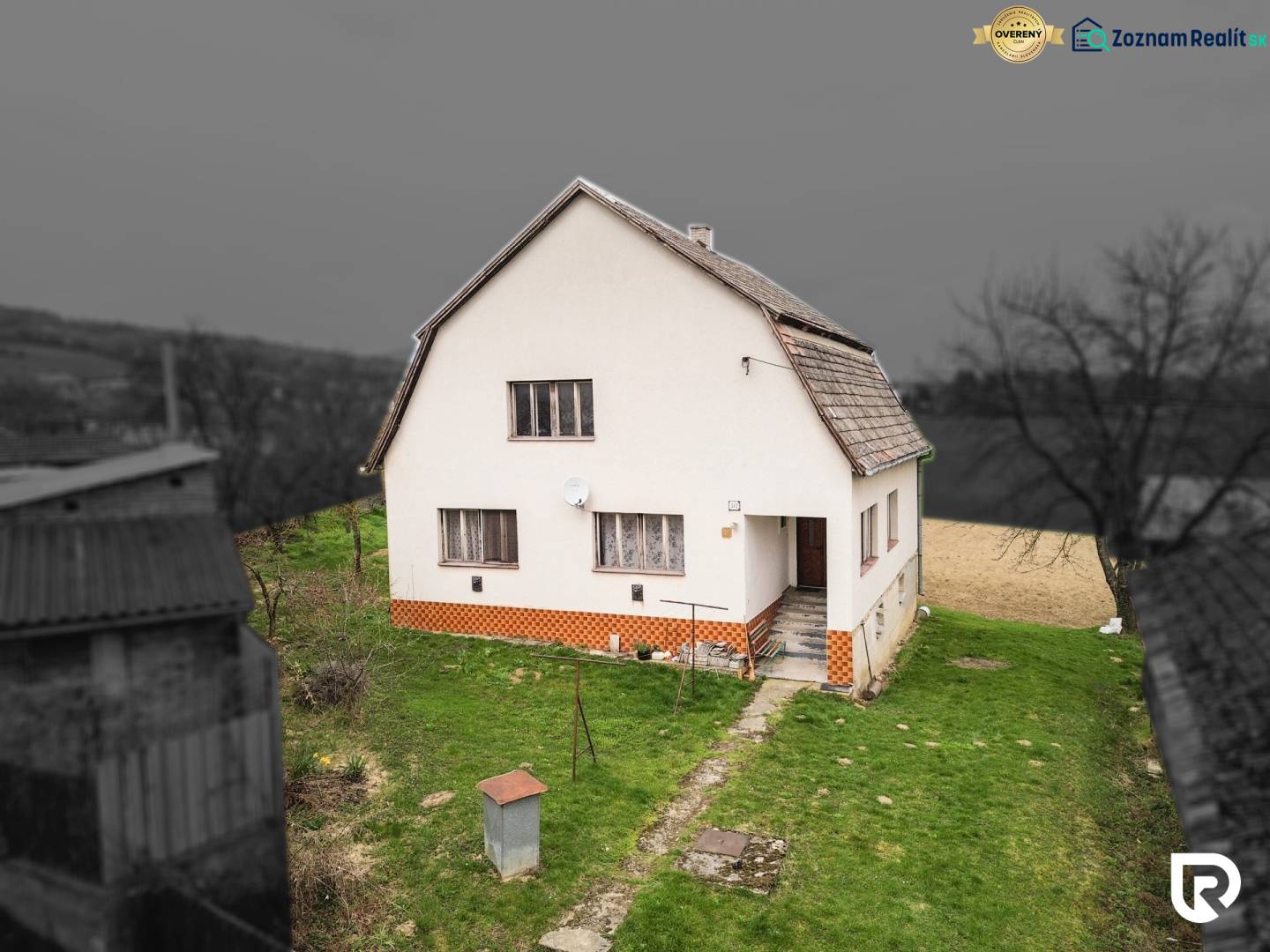 Dom s veľkým pozemkom 3099m2, Melčice-Lieskové - Rodinný dom so šikmou strechou, bielou fasádou a záhradou. Okolie je sivé.