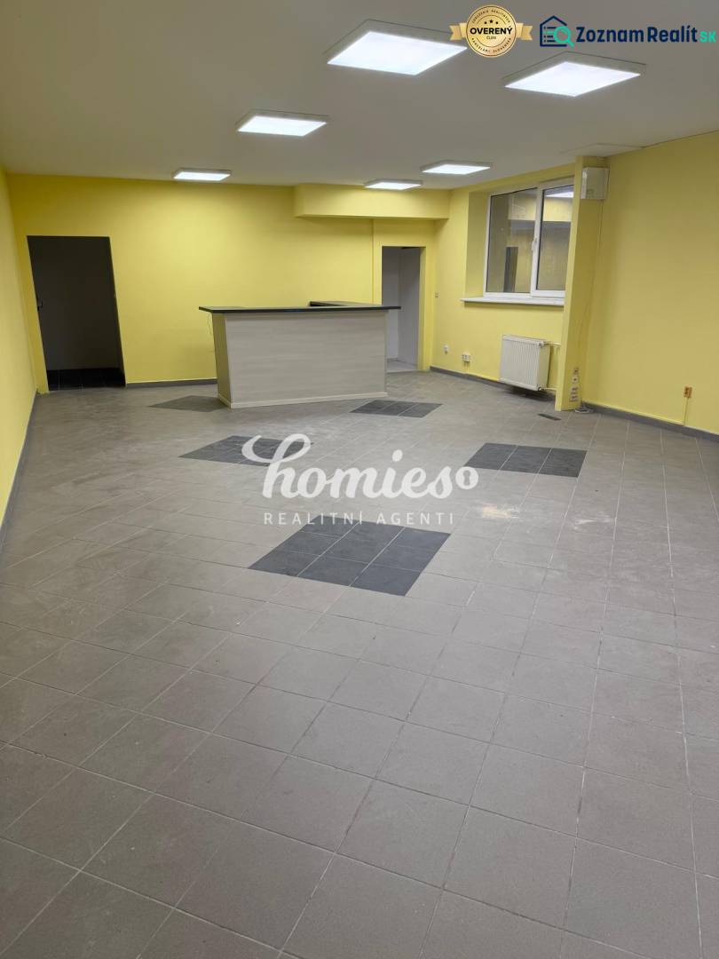 PRENÁJOM OBCHODNÉHO priestoru , NITRA - Štúrova ulica - Žlté steny, šedá podlaha a drevený pult v obchodných priestoroch.