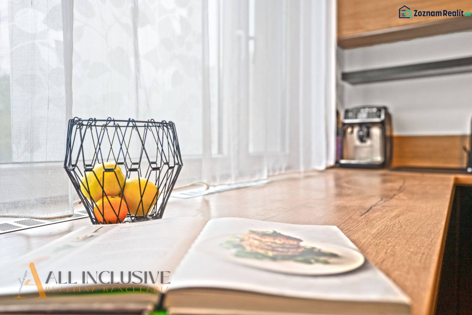 NA PREDAJ 3-IZBOVÝ BYT S PIVNICOU, SENEC - Otvorená kuchyňa v 3-izbovom byte s dreveným dekorom, miska s ovocím na stole.