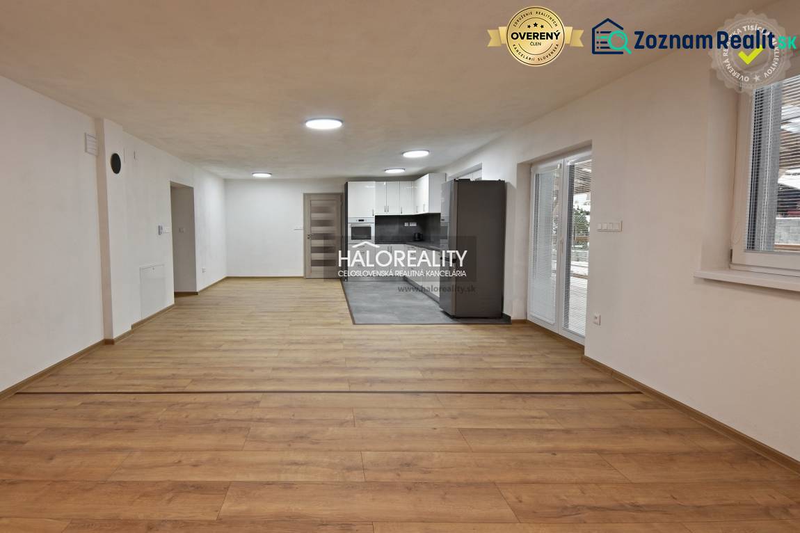 Prenájom, rodinný dom Nová Baňa - NOVOSTAVBA - EXKLU... - Obývačka v rodinnom dome s kuchyňou, podlaha s dreveným dekorom, biele steny.