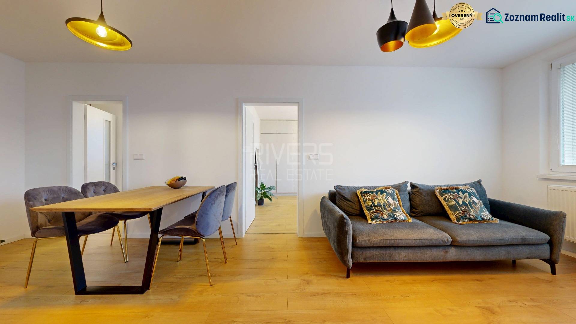 Kvalitne rekonštruovaný byt vo výbornej lokalite Petržalky - Obývačka 3-izbového bytu so salónikom, jedálenským stolom a podlahou s dreveným dekorom.