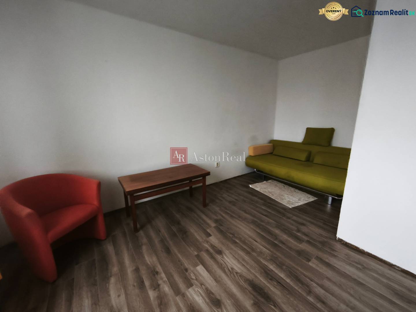 PREDAJ: 1i byt 30m2 - BAURING - FONČORDA - Orenburská ul. - 1-izbový byt s podlahou s dreveným dekorom, zelenou pohovkou a červeným kreslom.