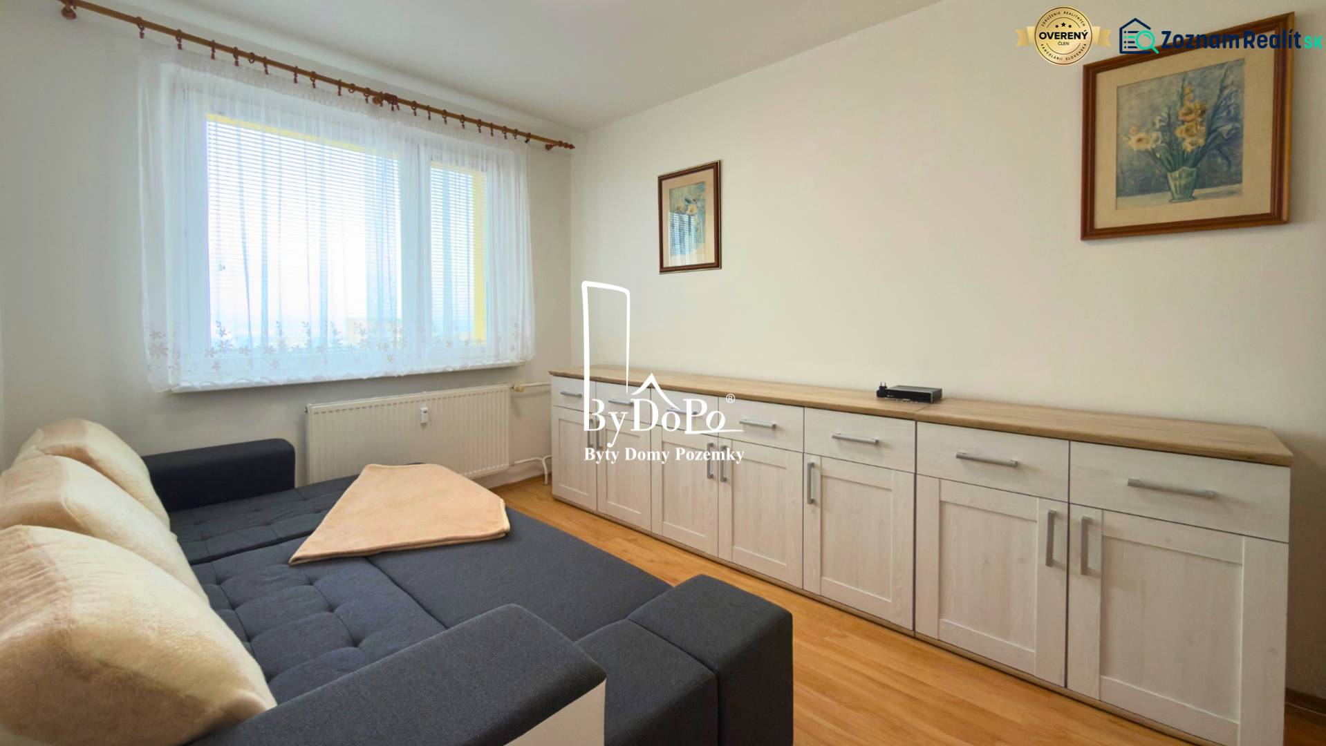 3-izbový zariadený byt, 78 m2, zasklenná loggia, Považská ul., Nitra - Izba s pohovkou, nábytkom a podlahou s dreveným dekorom v 3-izbovom byte.