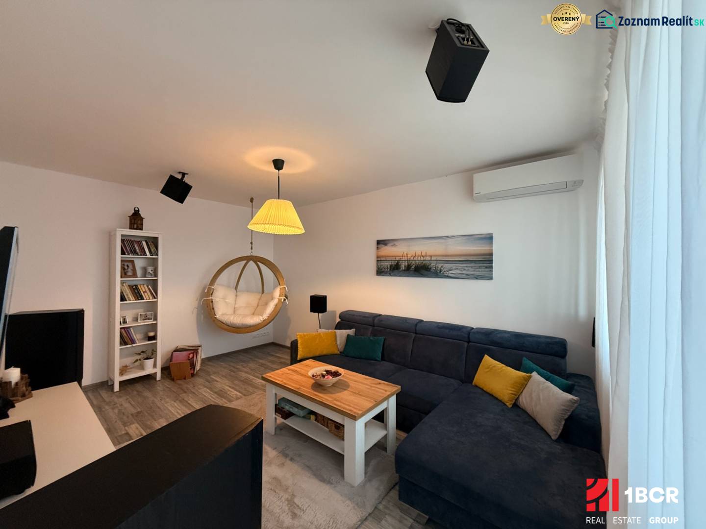 KRÁSNY, ÚTULNÝ A ŠTÝLOVÝ 3 IZBOVÝ BYT | DUBRAVKA - Obývacia izba v 3-izbovom byte s podlahou s dreveným dekorom a závesným kreslom.