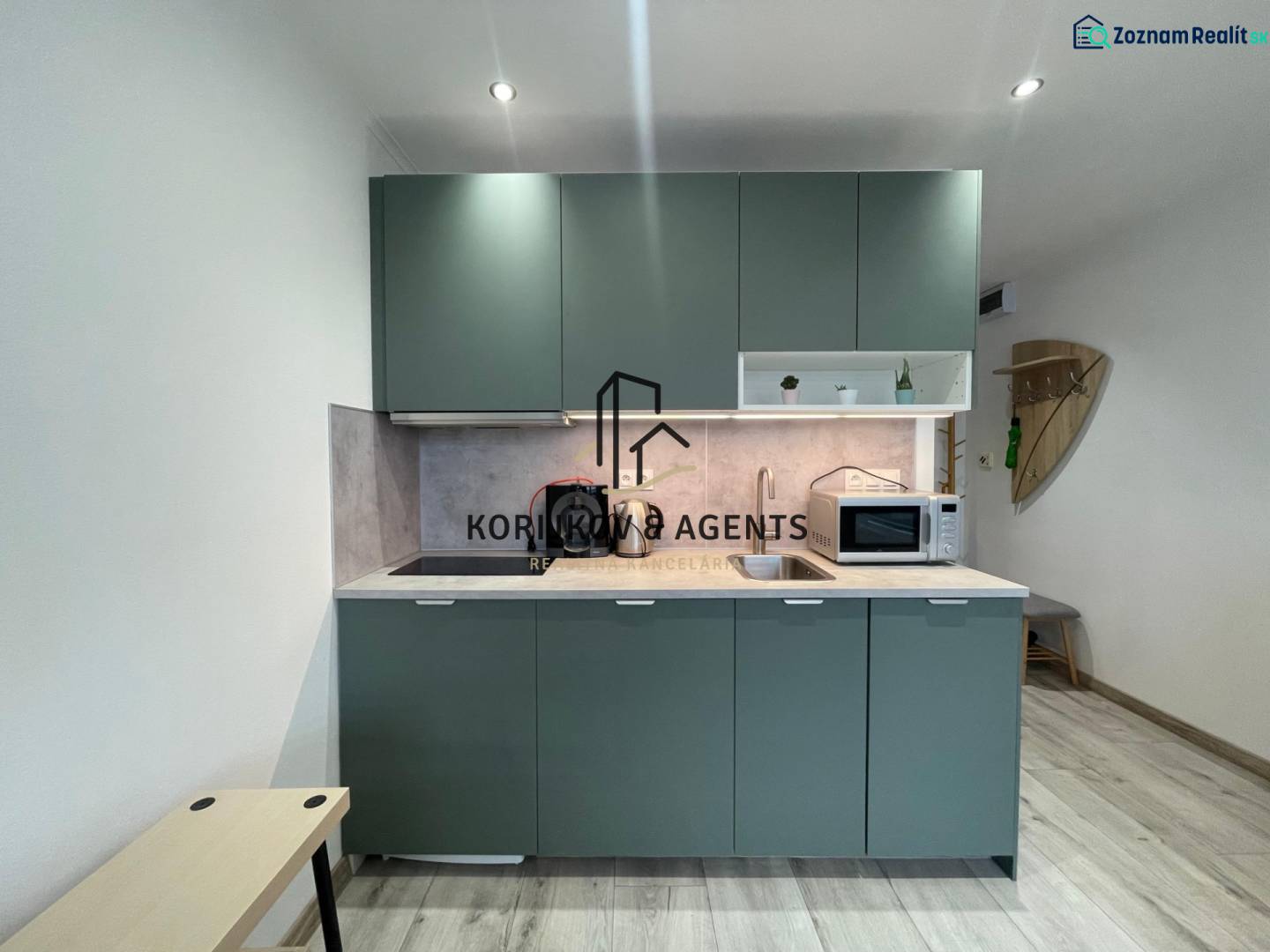 PRENÁJOM, garsónka na Jegorovovom námestí, Košice-Dargovských hrdinov - Kompaktná kuchyňa s mikrovlnkou a zelenými skrinkami v garsónke s podlahou s dreveným dekorom.