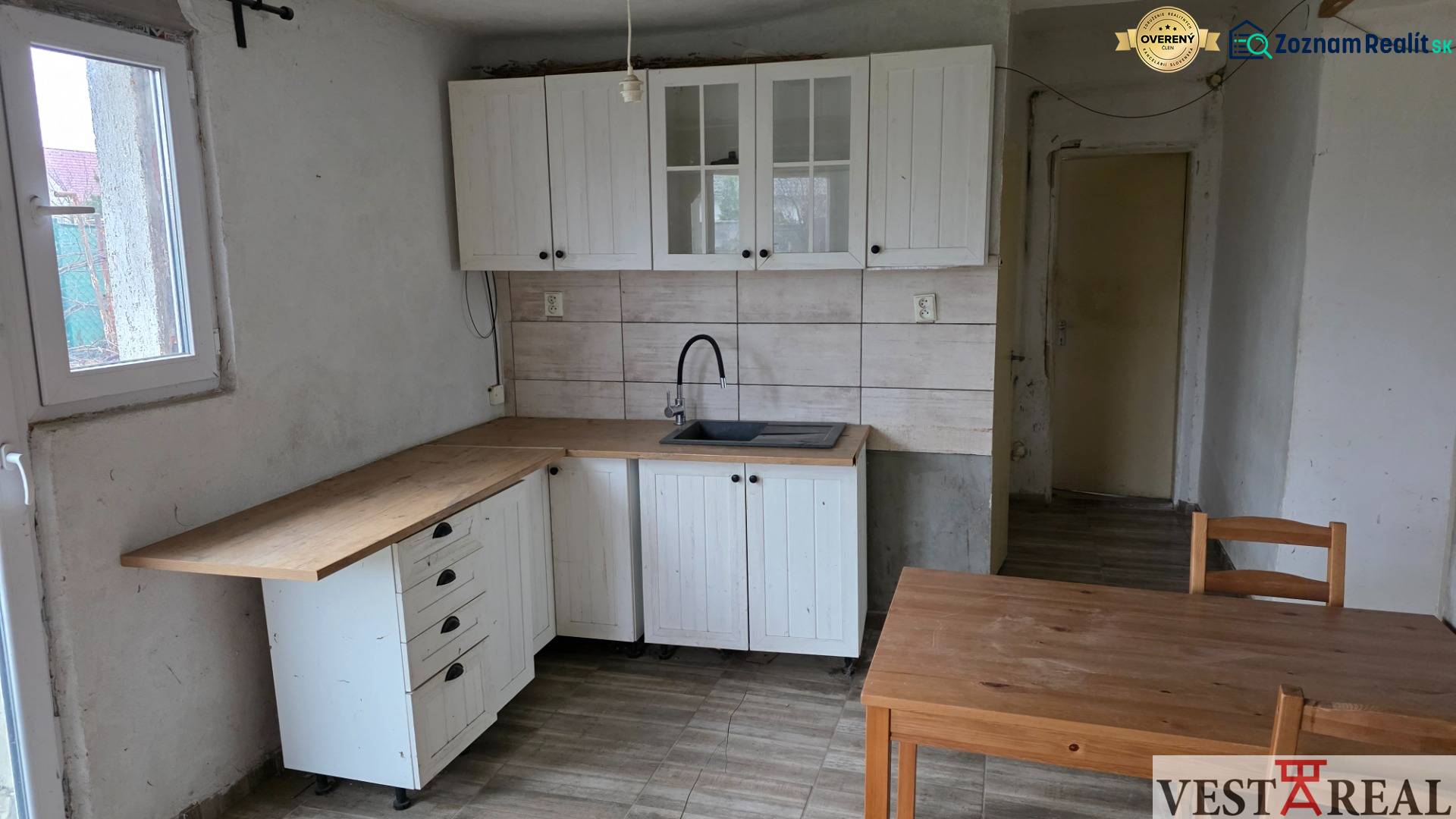 Na predaj 5 izbový rodinný dom Vinohrady nad Váhom - Kuchyňa v rodinnom dome s bielymi skrinkami a podlahou s dreveným dekorom.