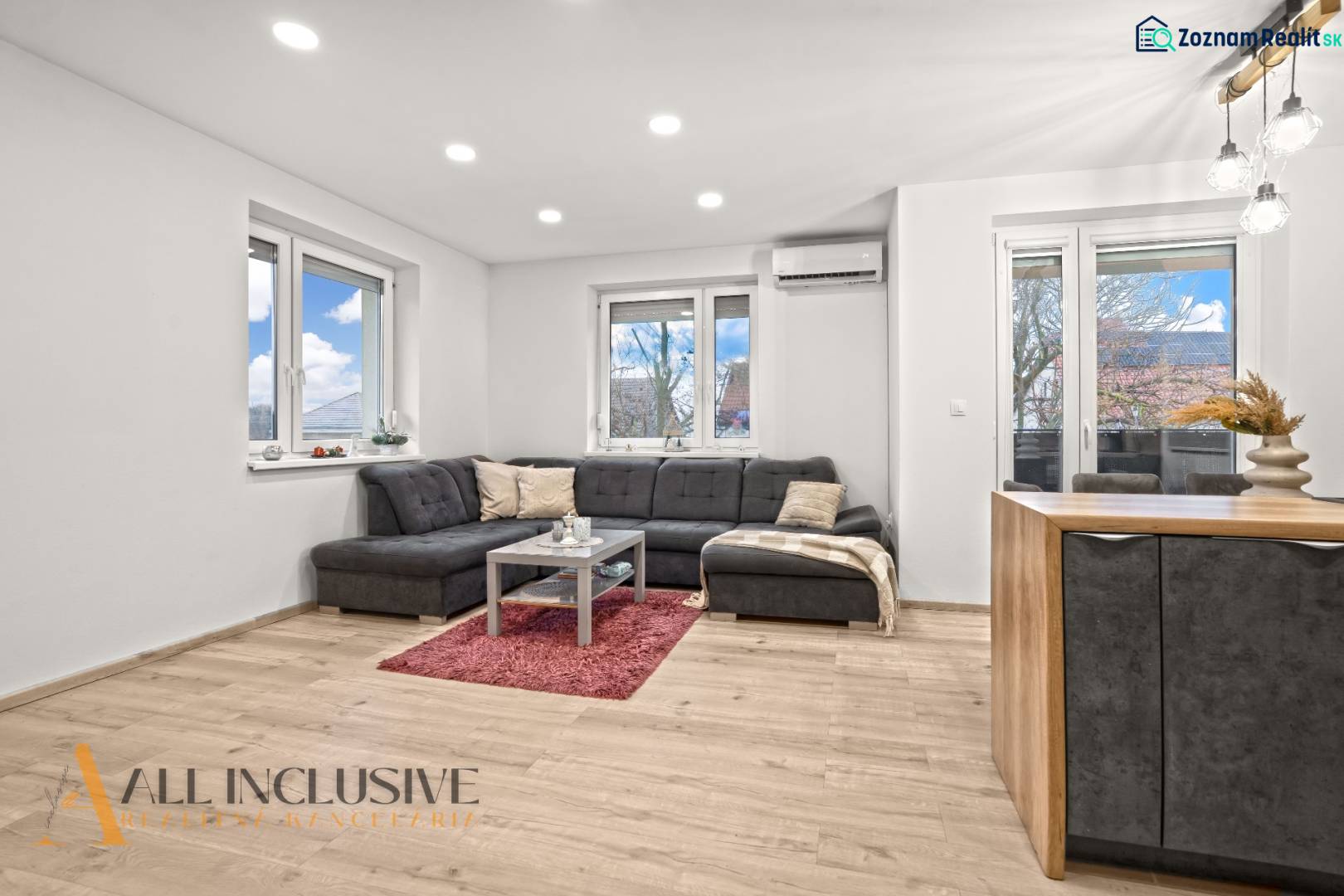 REZERVOVANÉ | NA PREDAJ 3-IZBOVÝ BYT S BALKÓNOM, VRAKÚŇ - Obývačka 3-izbového bytu s podlahou s dreveným dekorom, pohodlným sedením a veľkými oknami.