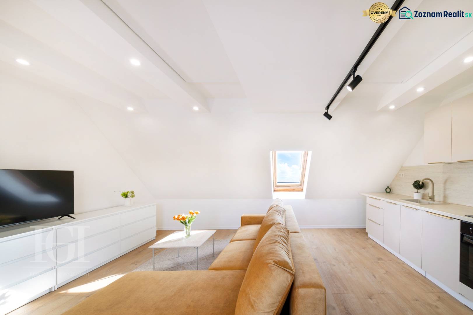  REZERVOVANY-PRENAJOM | NOVÝ 2 i. podkrovný byt v novostavbe - Svetlá obývacia izba s béžovou pohovkou, podlahou s dreveným dekorom a strešným oknom.