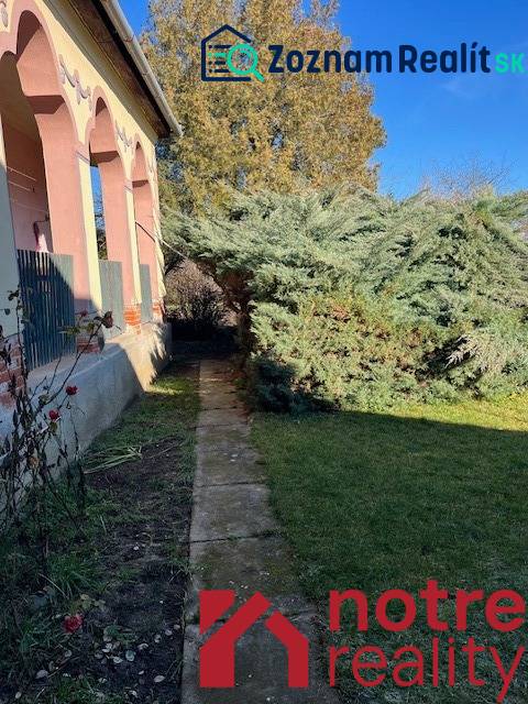 Prízemný rodinný dom v Tomášovciach  - Rodinný dom v Tomášovciach s predzáhradkou a veľkým stromom pri chodníku.