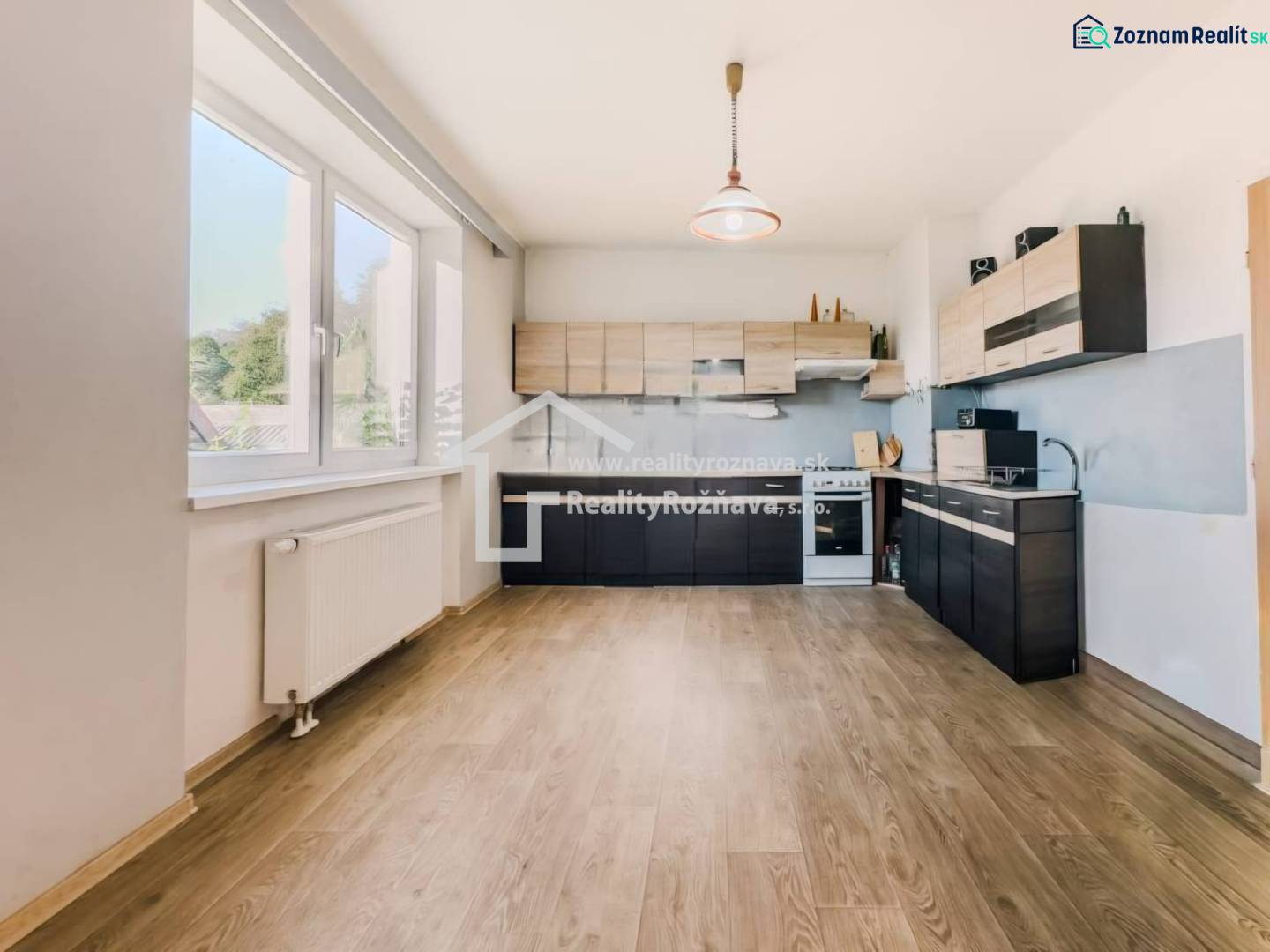 Rodinný dom vo vyhľadávanej obci Betliar. - Kuchyňa v rodinnom dome s podlahou s dreveným dekorom a veľkým oknom.