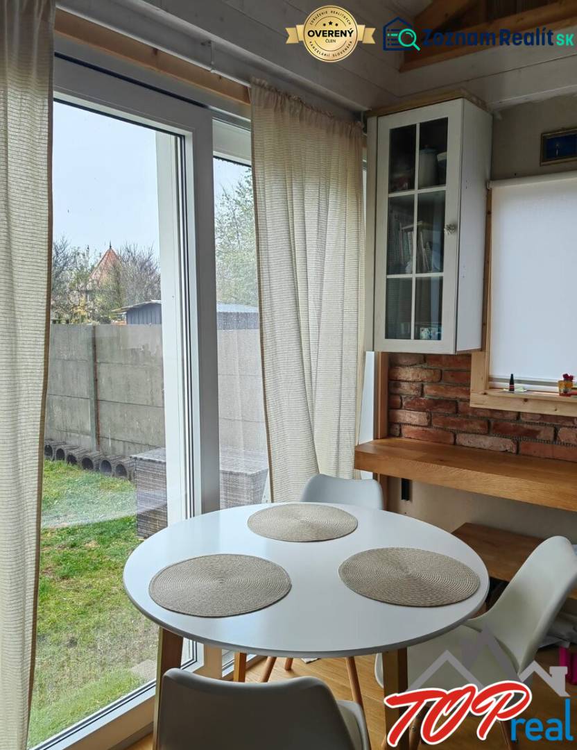 Tiny house - malý domček - Jedálenský kút v rodinnom dome s podlahou s dreveným dekorom, tehlovou stenou a veľkými oknami.