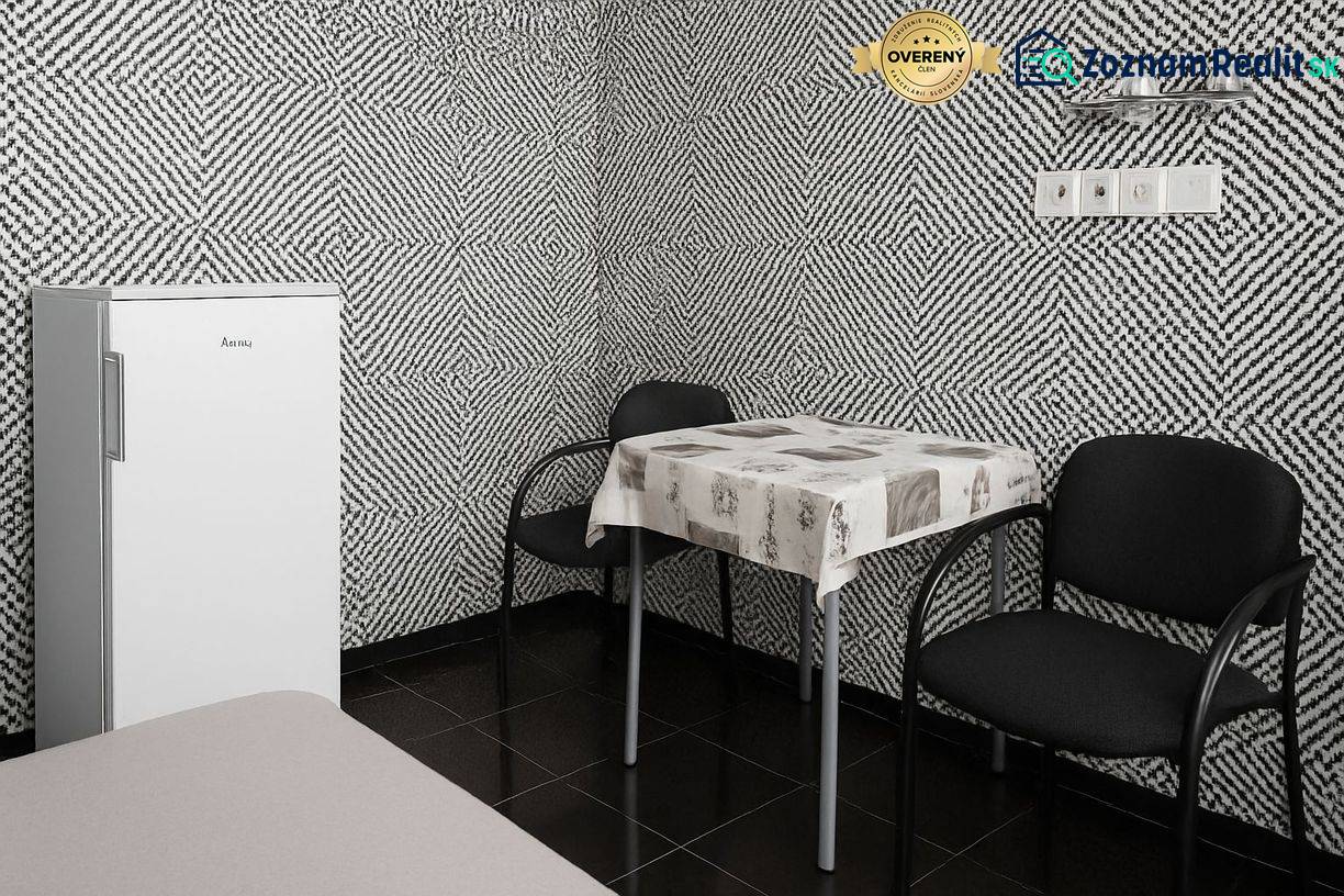 Prenájom ubytovacieho zariadenia – Šaľa Veča s kapacitou 50 osôb - Interiér s čiernobielou vzorovanou tapetou, samostatnou chladničkou, stolom a dvoma stoličkami.
