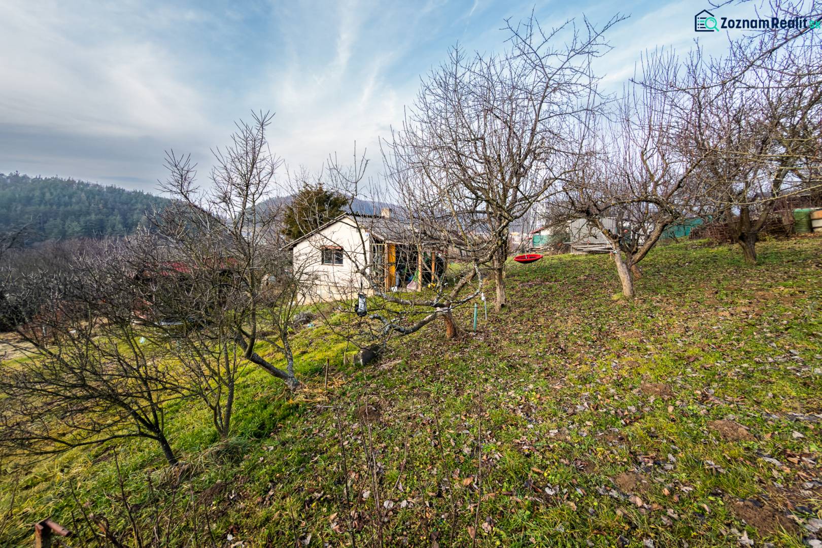 CHATKA SO ZÁHRADOU, PREŠOV – ŠIDLOVEC - Chata medzi ovocnými stromami na svahu v okolí Prešova počas zimy.