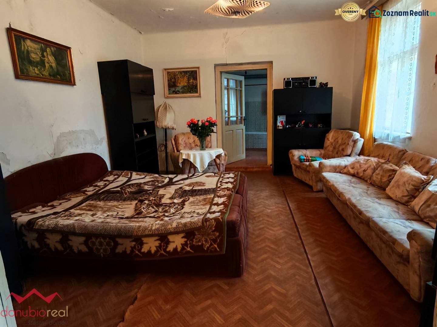 Na predaj rodinný dom v širšom centre mesta Komárno. - Obývacia izba v rodinnom dome s kvetmi, pohovkou a podlahou s dreveným dekorom.