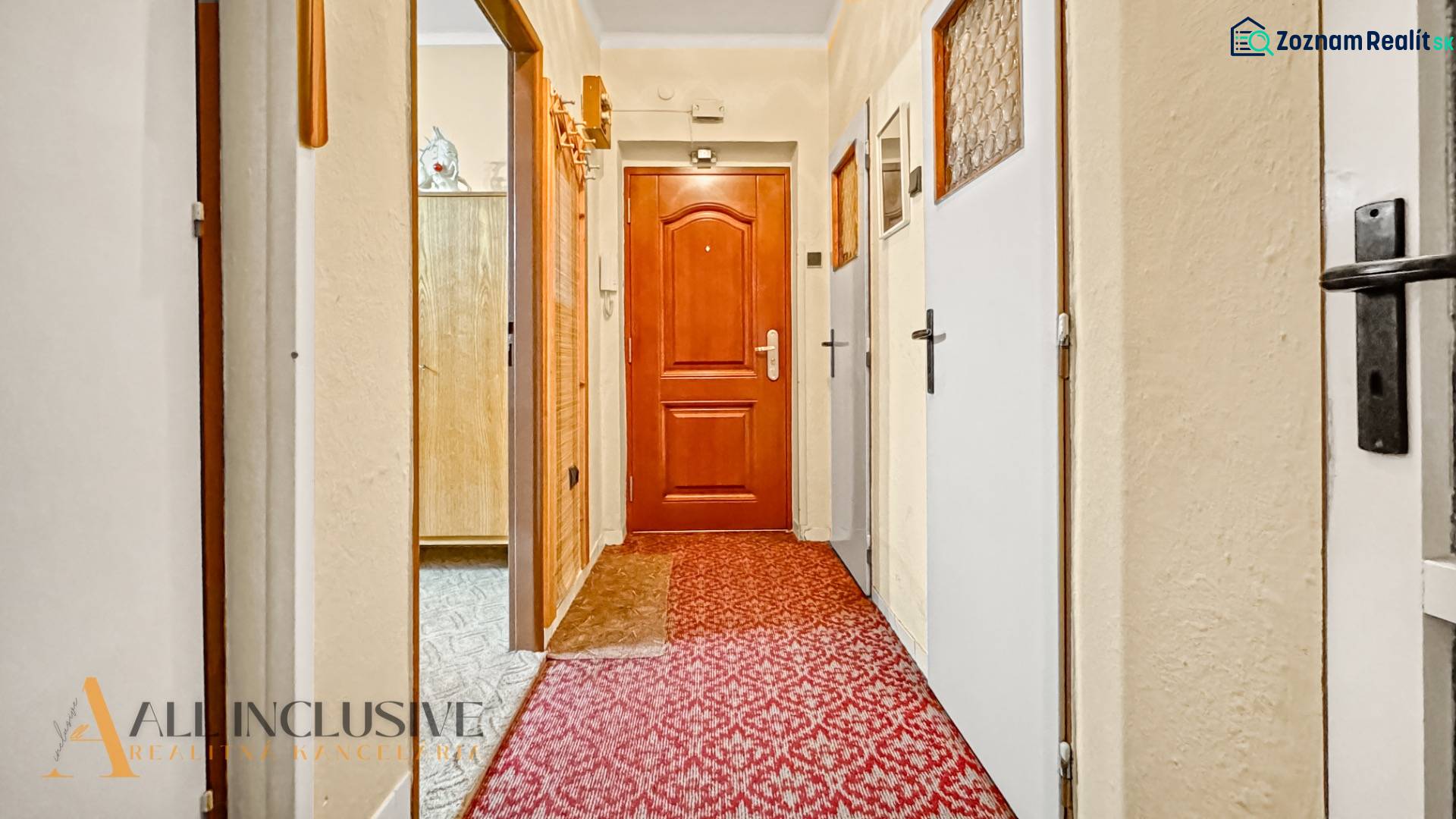 PRÍJEMNÝ 3 IZBOVÝ BYT | BOŠANY  - Chodba v 3-izbovom byte s červeným kobercom a drevenými dverami.