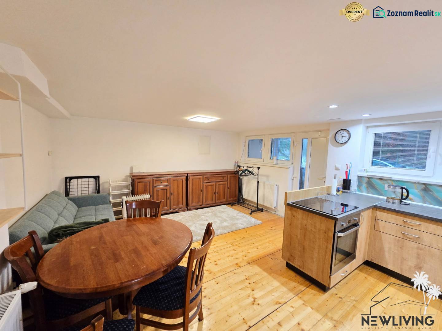 *PRENÁJOM* bezbariérový 1 izbový byt Lesná / Banka - Obývacia izba v 1-izbovom byte s podlahou s dreveným dekorom, sedačkou a jedálenským stolom.