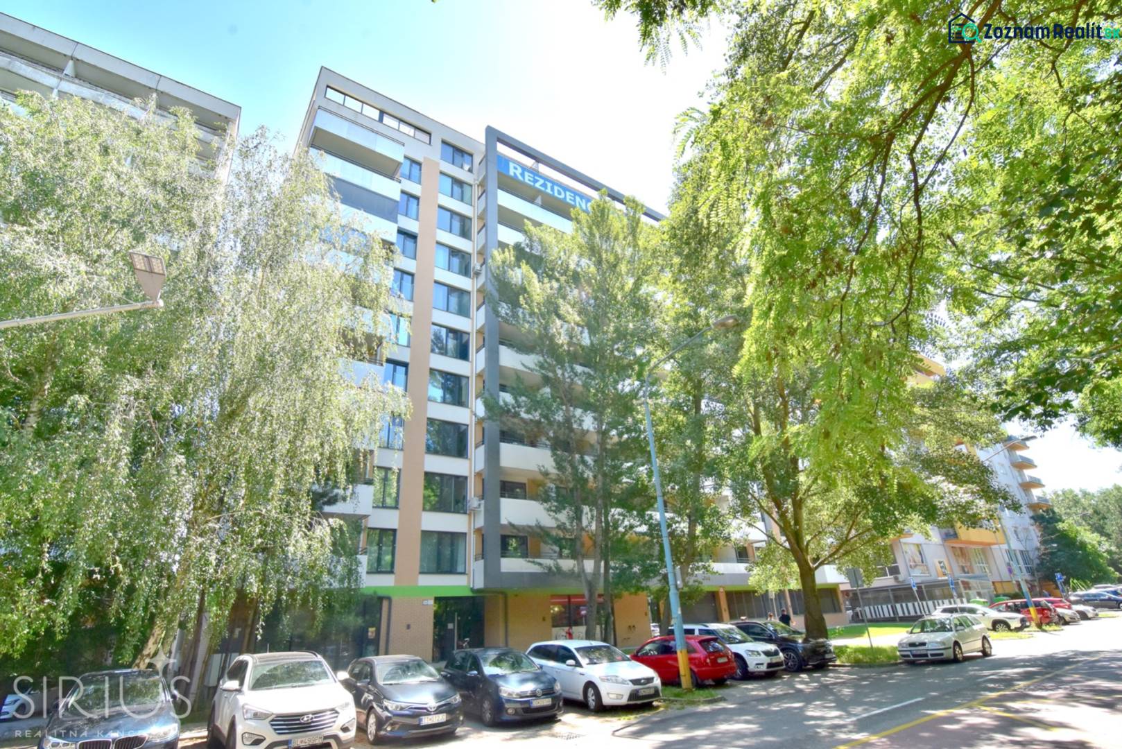 ANTOLSKÁ, 2-i byt, 54 m2 – novostavba REZIDENCIA DRAŽDIAK, zariadený - Bytový dom na Antolskej ulici v Bratislave - Petržalke, obklopený zeleňou a parkujúcimi autami.