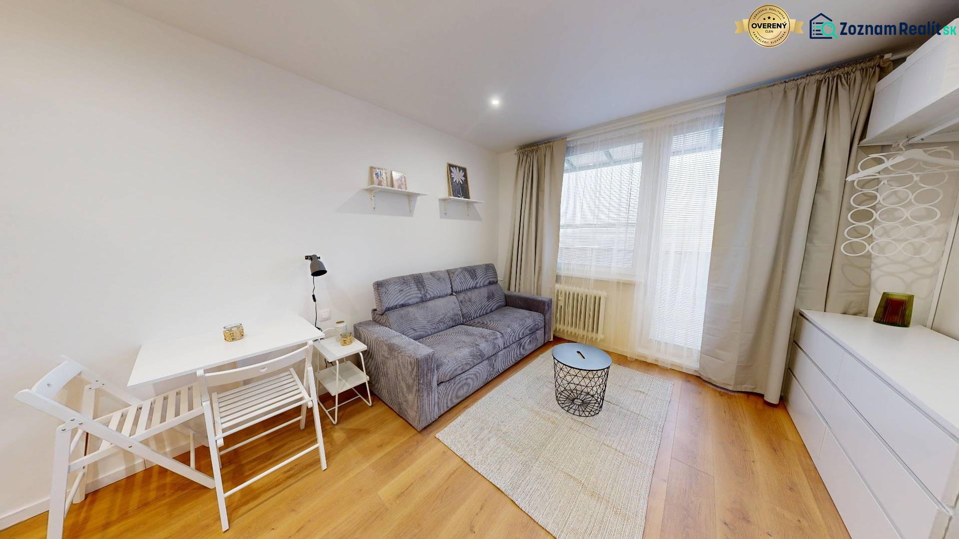  PRENÁJOM - Garsónka s balkónom Holíč, Lúčky 11 - Garsónka s podlahou s dreveným dekorom, sedačkou, stolíkom a bielym nábytkom.