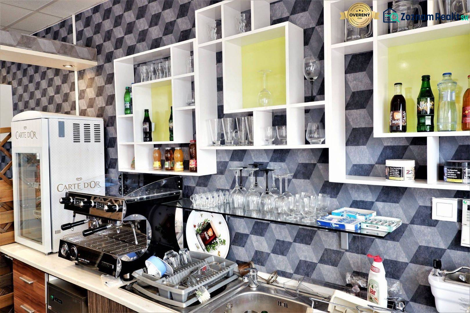 Kaviareň v Top lokalite mesta Šaľa na predaj - Interiér obchodných priestorov s kávovarom, regálmi, pohármi a nápojmi na poličkách.