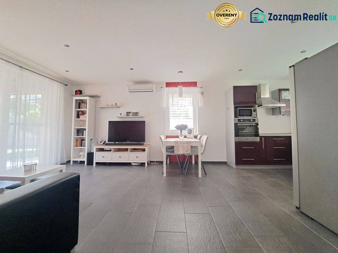 Predvianočná zľava! Na predaj krásny 4izb dom v obci Čierny Brod  - Obývacia izba s TV, kuchyňou a jedálenským stolom, podlaha s dreveným dekorom.