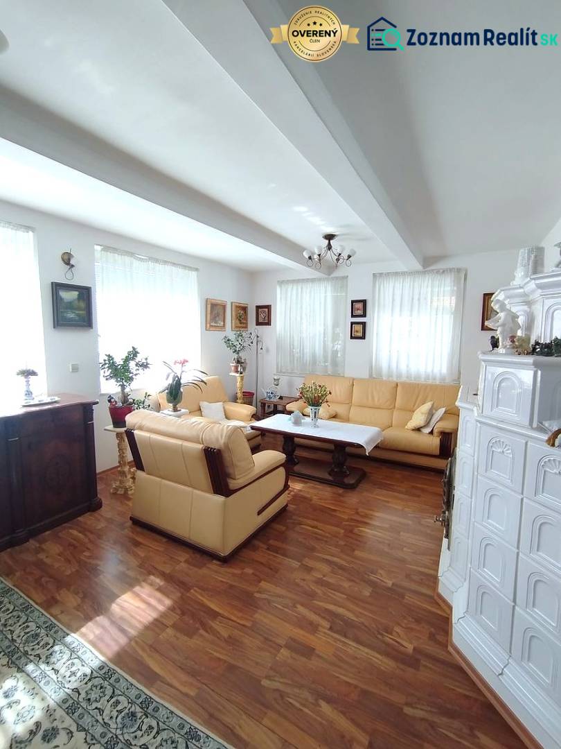 Predaj RD v Šali s bazénom - Obývačka rodinného domu s podlahou s dreveným dekorom, krbom a pohodlnou sedacou súpravou.