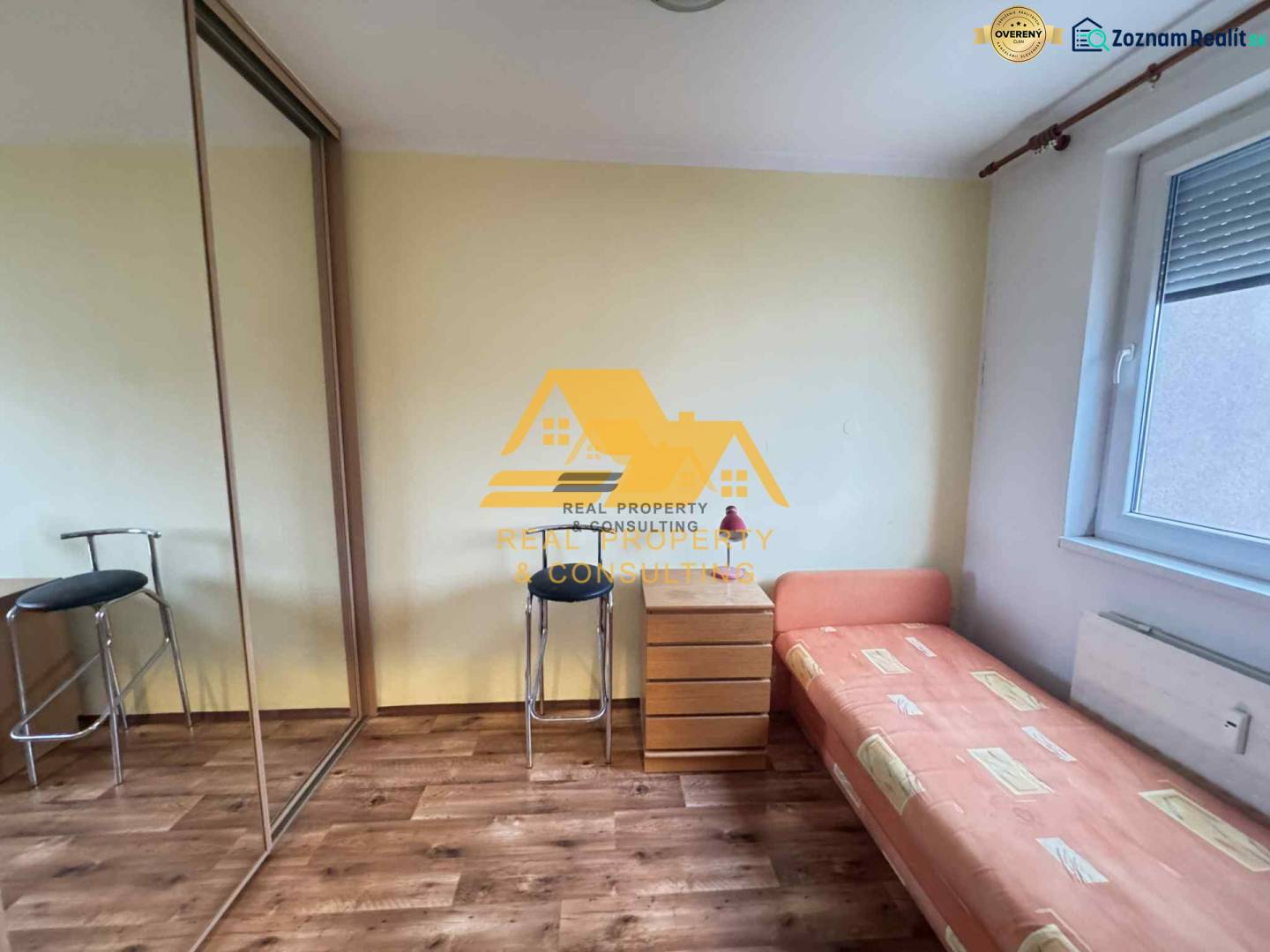 Prenajmem 3 izbový byt na sídlisku Juh v Nových Zámkoch - Izba s posteľou, skrinkou a podlahou s dreveným dekorom v 3-izbovom byte.