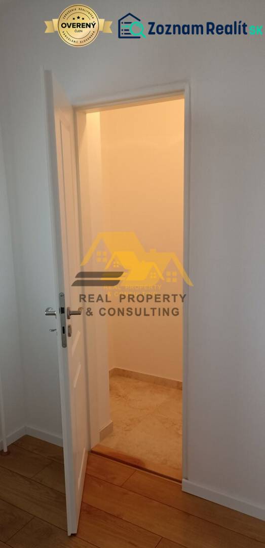 Prerobený 2 izbový byt s balkónom v Nových Zámkoch - Interiér 2-izbového bytu s otvorenými dverami a podlahou s dreveným dekorom.