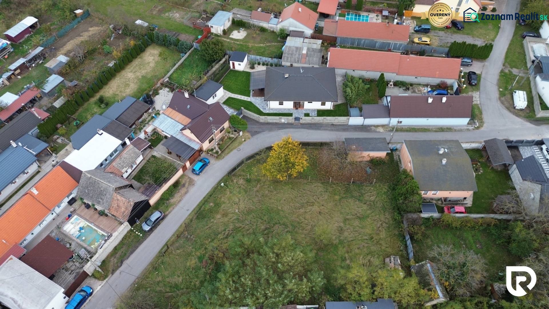 Stavebný pozemok 882 m² | Gajary - Letecký pohľad na obytné pozemky v Gajaroch s priľahlou cestou a domami.