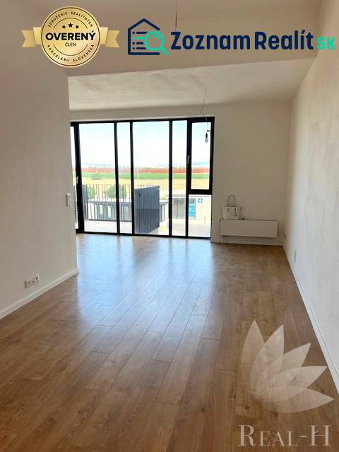 PREDAJ VEĽKORYSÝ 2 IZBOVÝ BYT NOVOSTAVBA DESINGN CENTER - Svetlá obývacia izba s veľkými oknami a podlahou s dreveným dekorom v 2-izbovom byte.