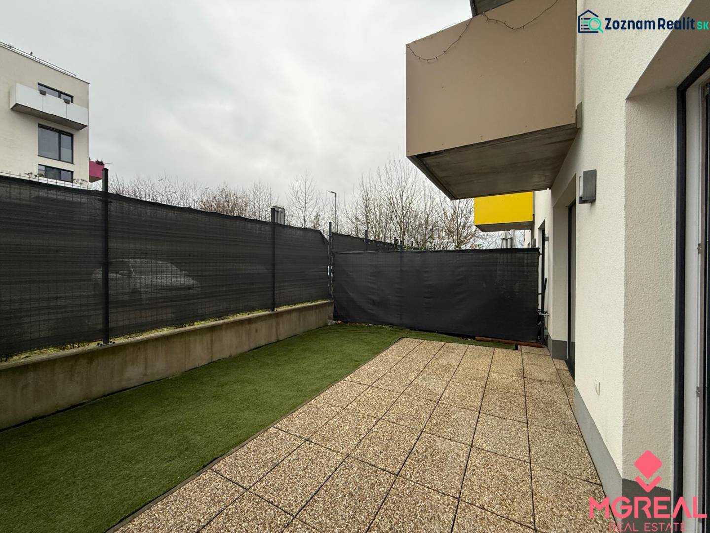 Novostavba 2 izbový byt s terasou a garážovým parkovacím miestom Nitra - Terasa pri 2-izbovom byte na Hornostavskej ulici v Nitre, s výhľadom na susedné budovy.