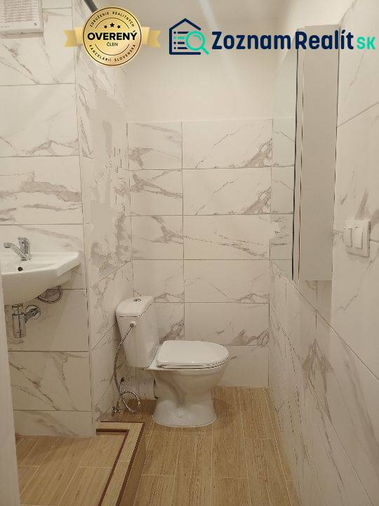 Prenájom veľmi peknej garzónky na Nábrežnej ulici - Kúpeľňa garsónky s toaletou, umývadlom a podlahou s dreveným dekorom.