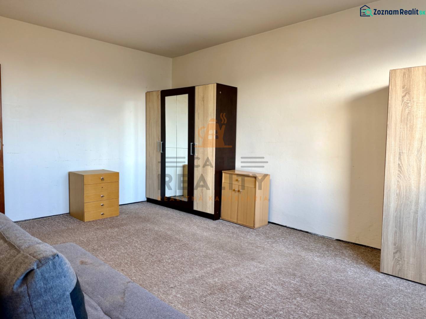 REZERVOVANÉ Na predaj 1 izbový byt, Bratislava, Dúbravka, Drobného - Izba v 1-izbovom byte s komodou, skriňou a kobercom na podlahe.