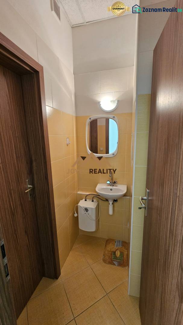 Na prenájom: Nebytový-obchodný priestor – Budovateľská ulica, Šaľa - Kúpeľňa v obchodných priestoroch s umývadlom a zrkadlom, obložená svetlými kachličkami.
