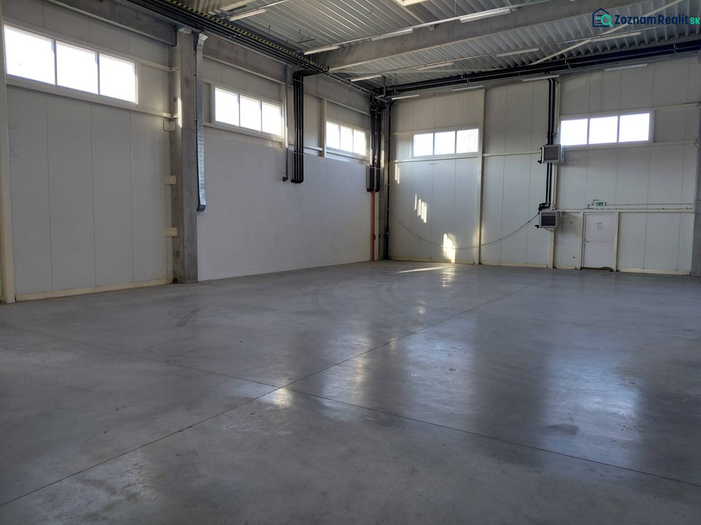 Prenájom skladu 670 m2 neďaleko letiska, IKEA - Pohľad do prázdnej haly so svetlými stenami v skladoch a halách.
