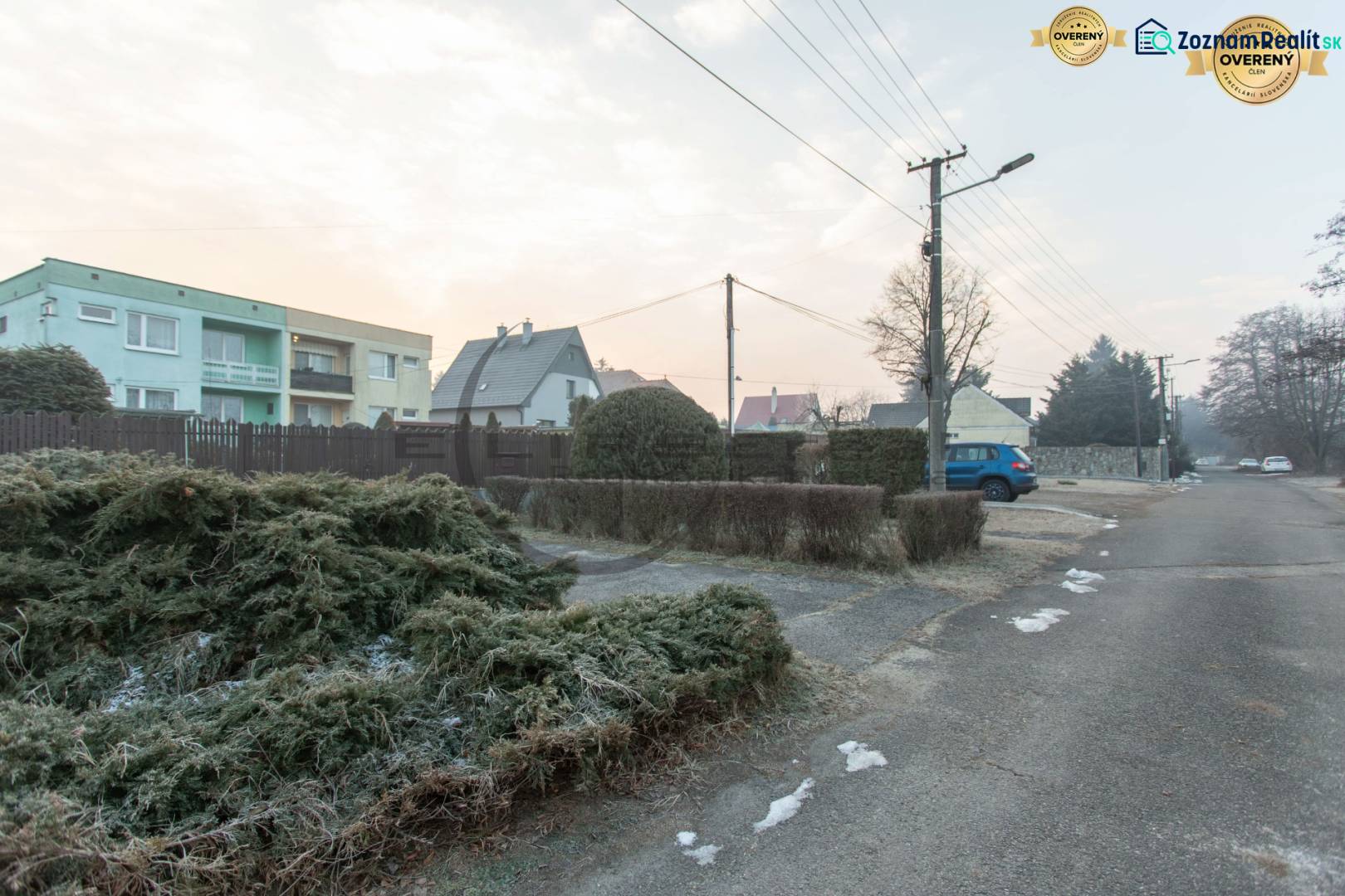 NA PREDAJ priestranný 4-izbový rodinný dom v Plaveckom Štvrtku - Ulica v Plaveckom Štvrtku so zástavbou rodinných domov, parkovacími miestami a elektrickými stĺpmi.