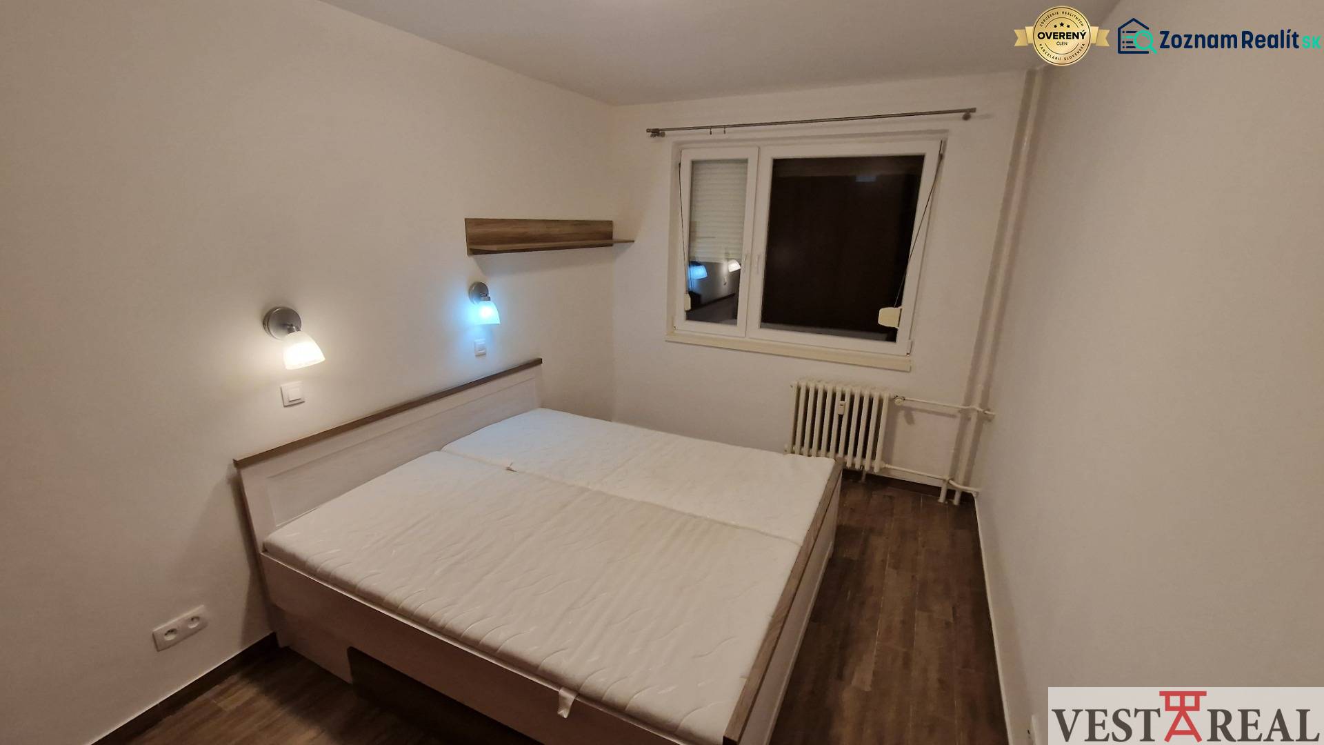 Na prenájom zariadený 3 izbový byt s balkónom Galanta- Mierová - Spálňa v 3-izbovom byte s posteľou, nočnými lampami a podlahou s dreveným dekorom.