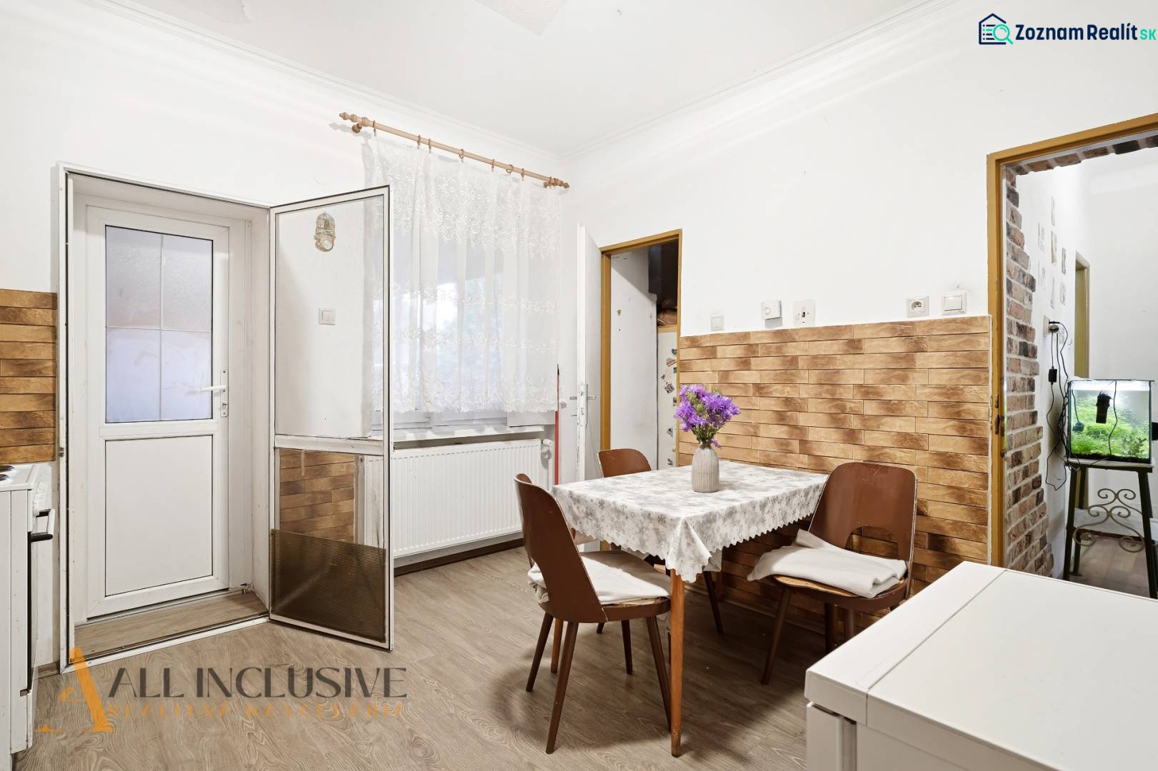 Na predaj 4-izb. rodinný dom s garážou, Okoč - Jedáleň v rodinnom dome s podlahou s dreveným dekorom a kvetmi na stole.