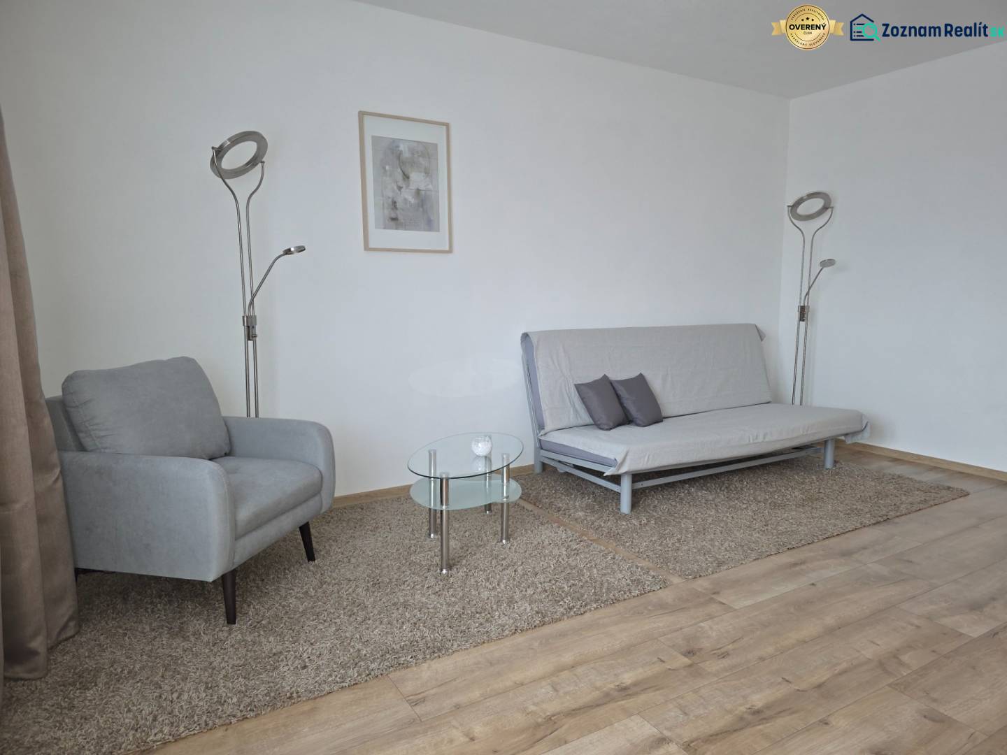 PRENÁJOM - Priestranný 3 izbový byt - Nitra, Centrum - Obývacia izba s kreslom, pohovkou a podlahou s dreveným dekorom v 3-izbovom byte.