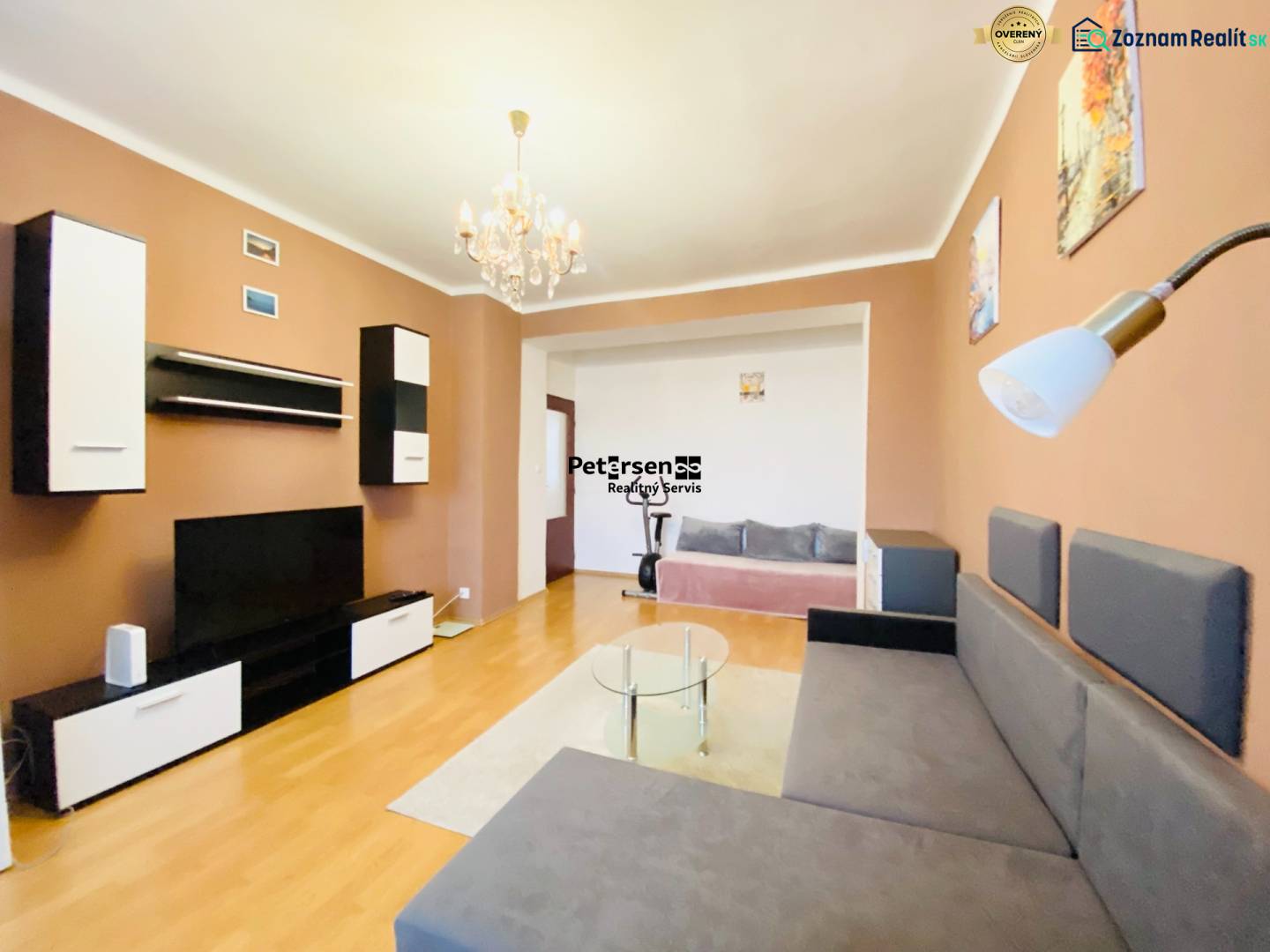 NA PRENÁJOM 2-IZBOVÝ BYT, NÁRODNÁ TRIEDA - Obývačka v 2-izbovom byte s podlahou s dreveným dekorom a pohodlnou sedačkou.