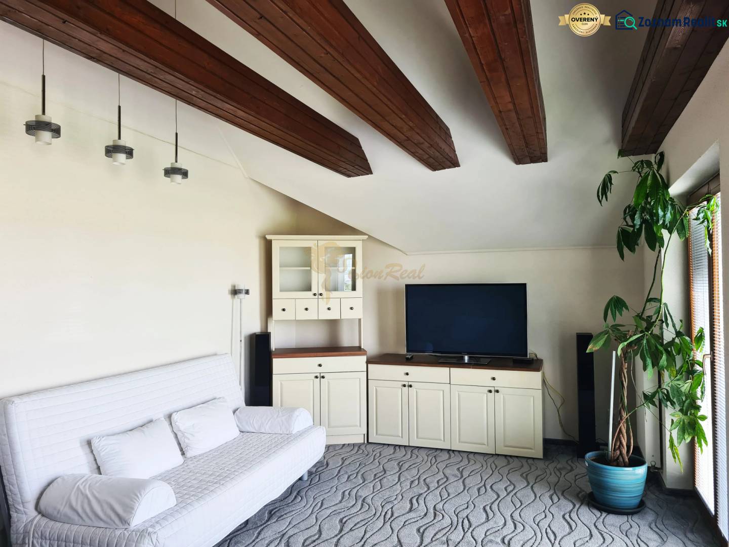 5-izb. dvojpodlažný rodinný dom, Rovinka - Obývačka v rodinnom dome so stropnými trámami, pohovkou, televíziou a veľkou rastlinou.