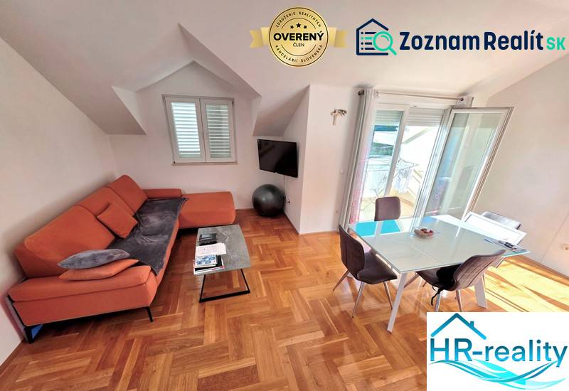 Chorvátsko, Makarska - zariadený apartmán s výhľadom na more - Rekreačný apartmán ponúka pohovku, jedálenský stôl a podlahu s dreveným dekorom.