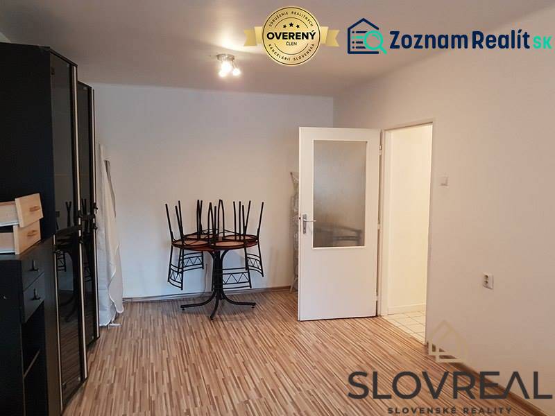 PREDAJ 2 IZBOVÝ BYT HANDLOVÁ  - Obývacia izba s drevenou podlahou, stolom a stoličkami v 2-izbovom byte.