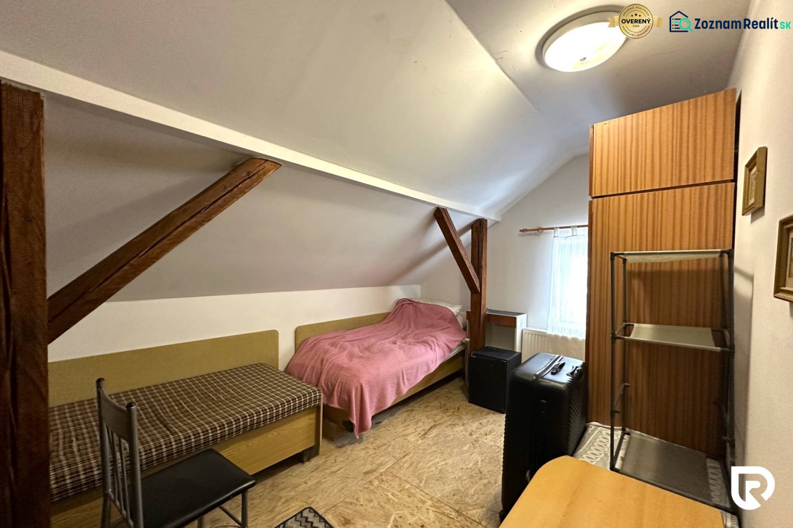 Na predaj dom vhodný na podnikanie sídlisko SNP v P. Bystrici! - Podkrovná izba v rodinnom dome s jednoduchým nábytkom a strešnými trámami.