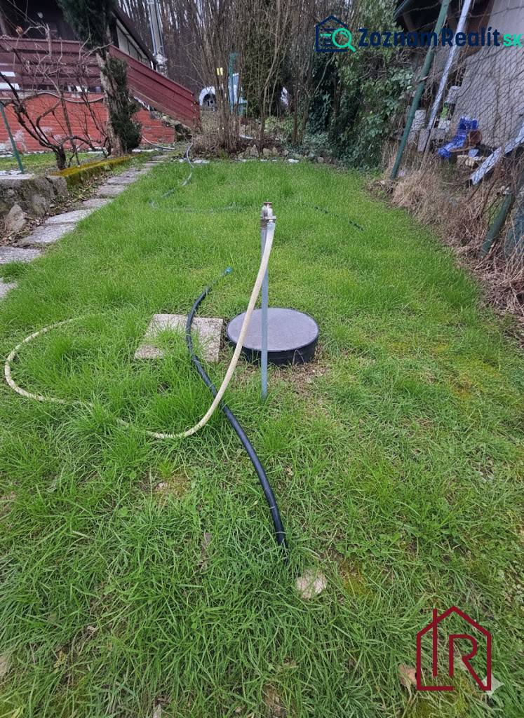 KH-1045, Slnečný pozemok s chatou na skok od Košíc, Šemša - Záhrada pri chate v Šemši, trávnik so studňou a hadicou.