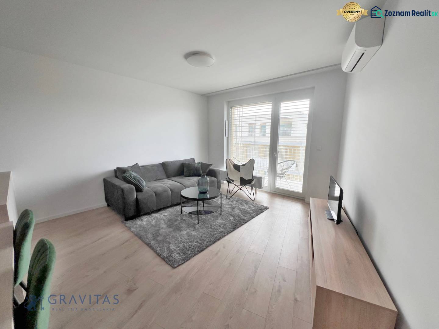 Na prenájom kompletne zariadený 2i byt s parkingom, Nový Ružinov - Obývacia izba v 2-izbovom byte s pohovkou, televízorom a podlahou s dreveným dekorom.