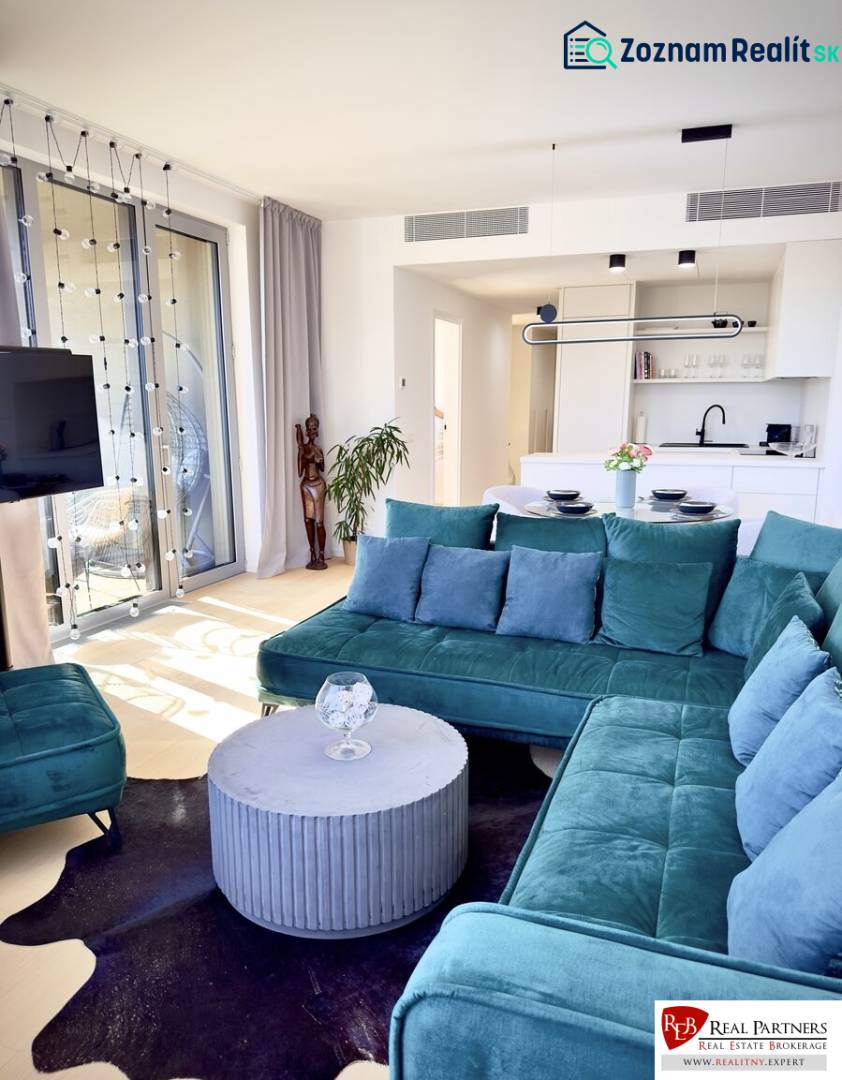 Prenájom 3-izbový byt s loggiou, SKY PARK, Bratislava - Obývacia izba v 3-izbovom byte so zelenou sedačkou a kuchynským kútom.