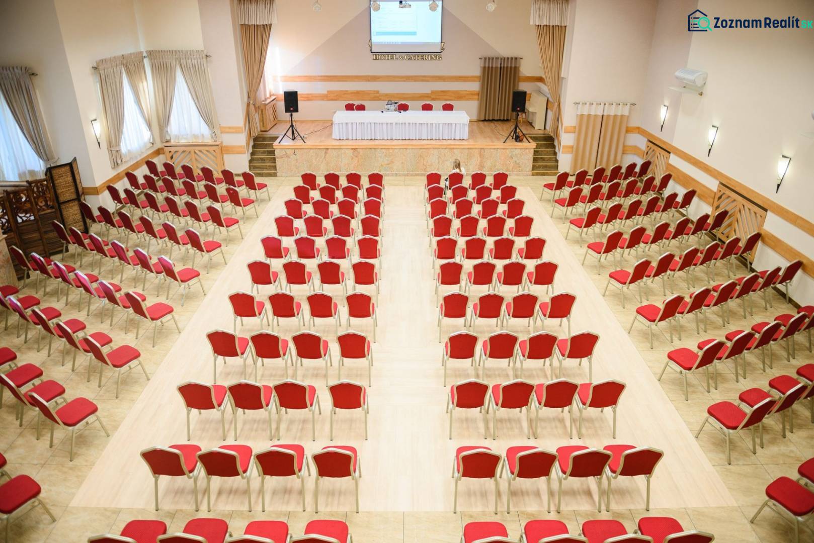 Predaj lukratívneho polyfunkčného objektu v Poprade - Konferenčná miestnosť s červenými stoličkami a podlahou s dreveným dekorom v Hoteloch a penziónoch.