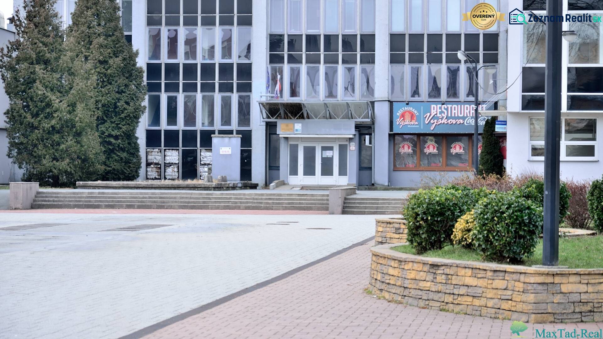 Kancelária s výhľadom na centrum Michaloviec. 16 m2 - Budova s kanceláriami na Námestí slobody v Michalovciach, obklopená zeleňou a chodníkmi.